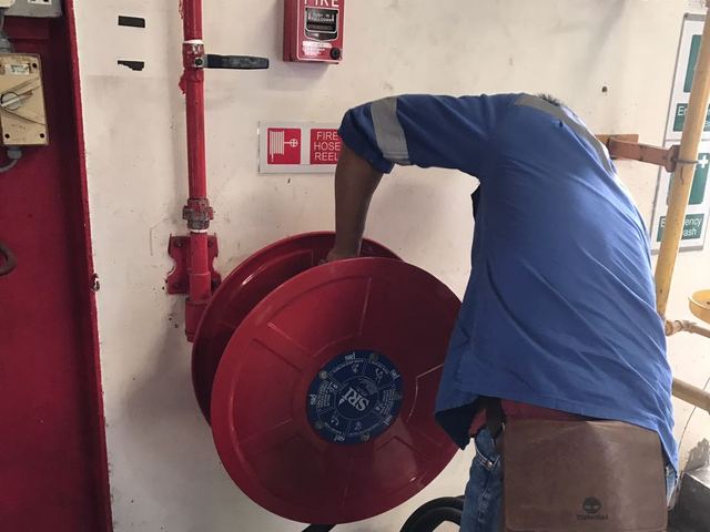 Technician inspecting a fire hose reel